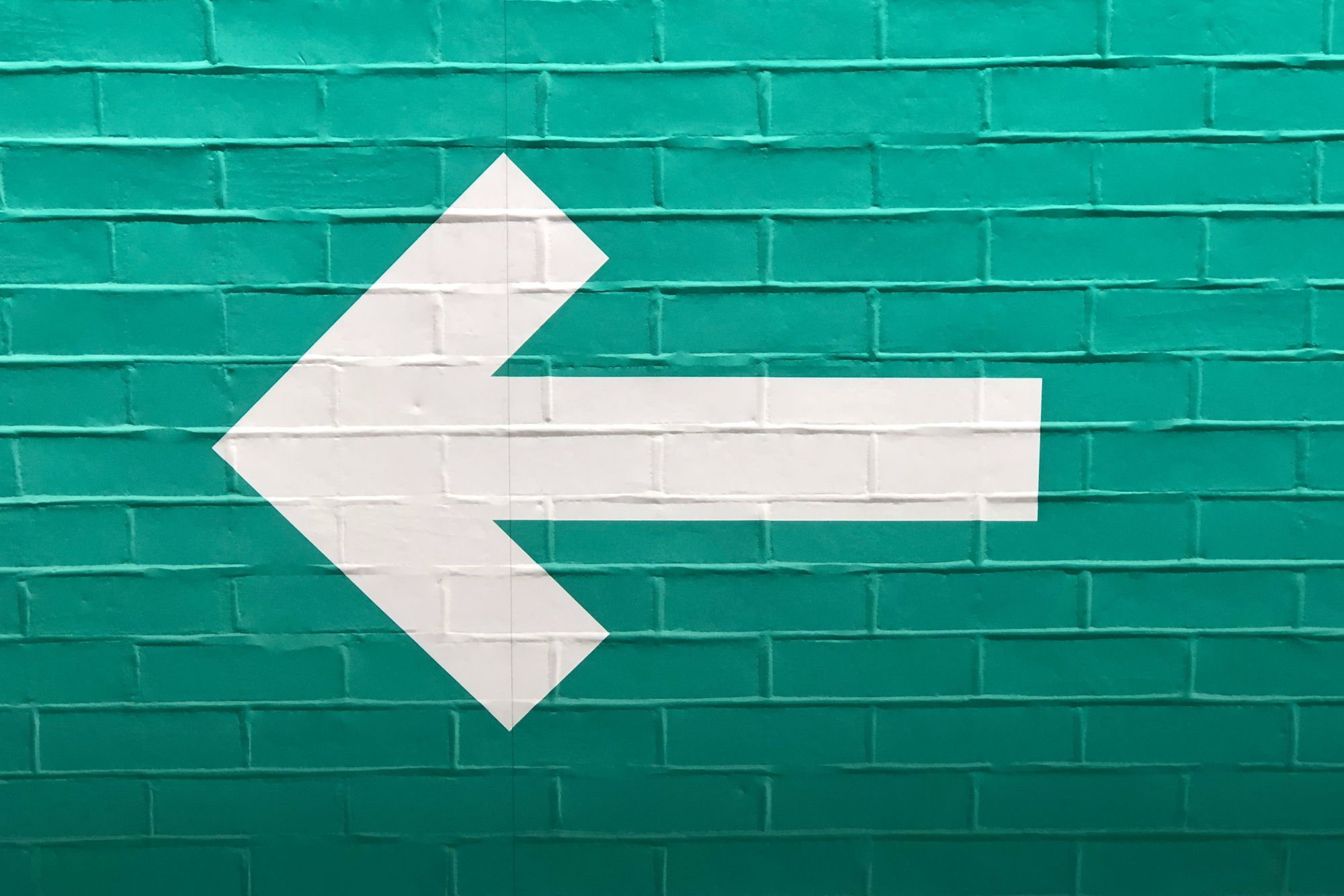 White arrow on blue bricks pointing left.